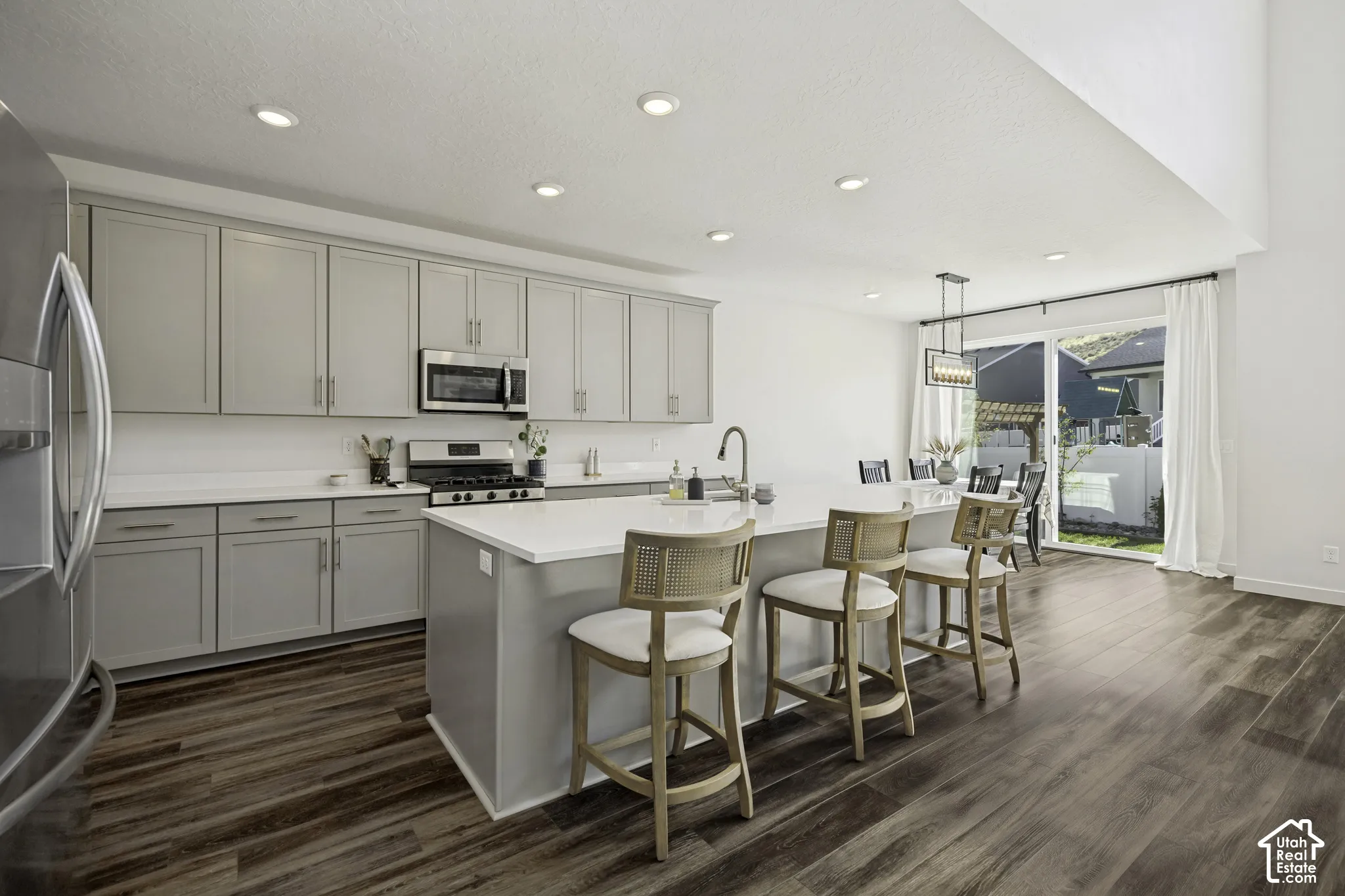 Modern kitchen featuring light gray cabinetry, stainless steel appliances, and wood-finish flooring