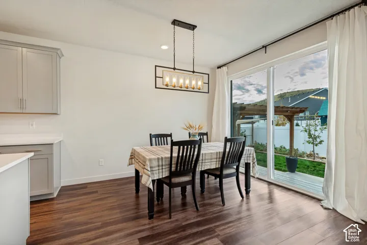 Wood-finish flooring, contemporary chandelier, sliding glass door, patio with pergola, and gray cabinetry