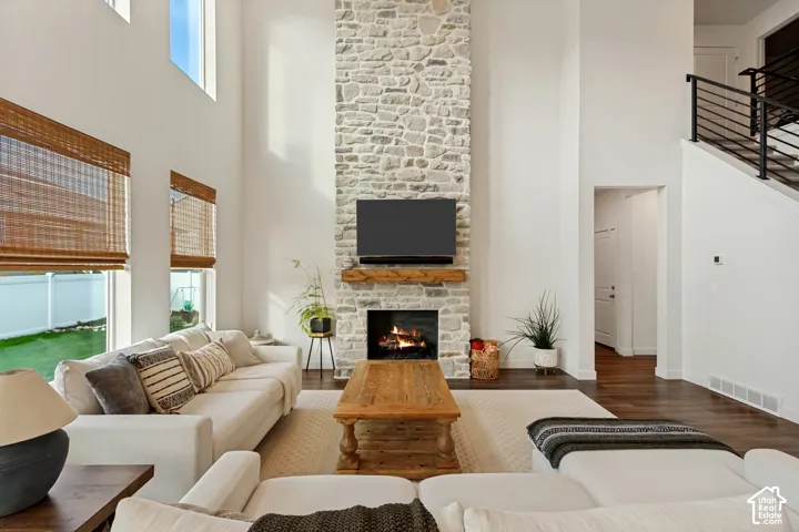 Two-story living area with high ceilings, a stone-clad fireplace, and a wood mantel