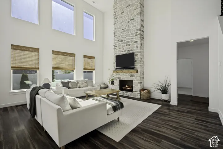 Vaulted ceilings, a full-height stacked stone fireplace with a wood mantel, wood-finish flooring, and multiple large windows