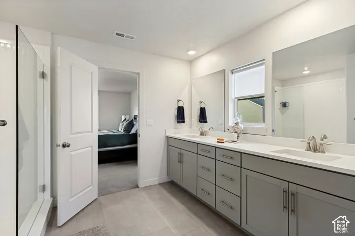 Double vanity with gray cabinetry, white countertops, and dual mirrors