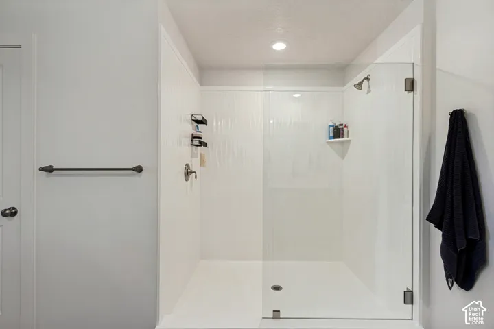 Glass-enclosed shower with white paneling and a built-in shower niche