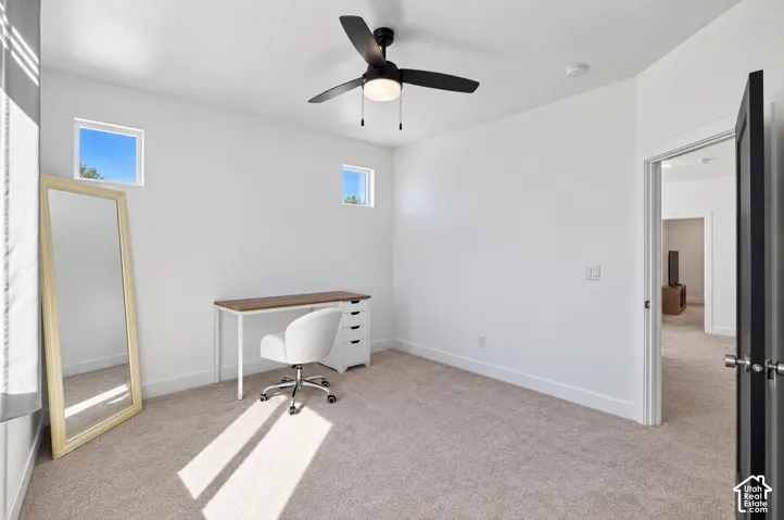 Carpeted room featuring high ceilings, two transom windows, a black ceiling fan with integrated lighting, and a white door with dark hardware