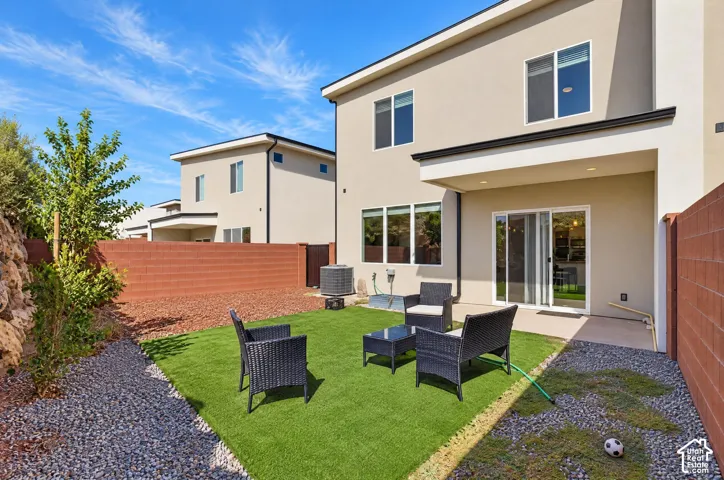 Expansive backyard featuring artificial turf, gravel landscaping, and a privacy wall
