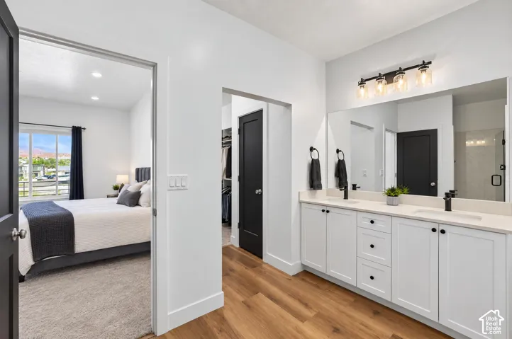Double vanity with undermount sinks, wood-finish flooring, and a large mirror