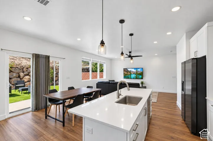Open-concept living space featuring wood-finish flooring, recessed lighting, and a kitchen island with an undermount sink and white countertop