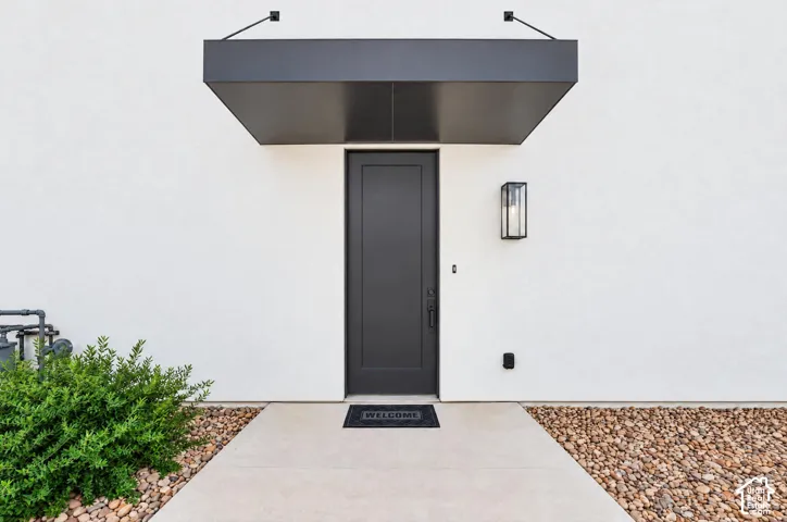Modern entry with a dark-tone door, contemporary wall sconce, and matching overhead awning