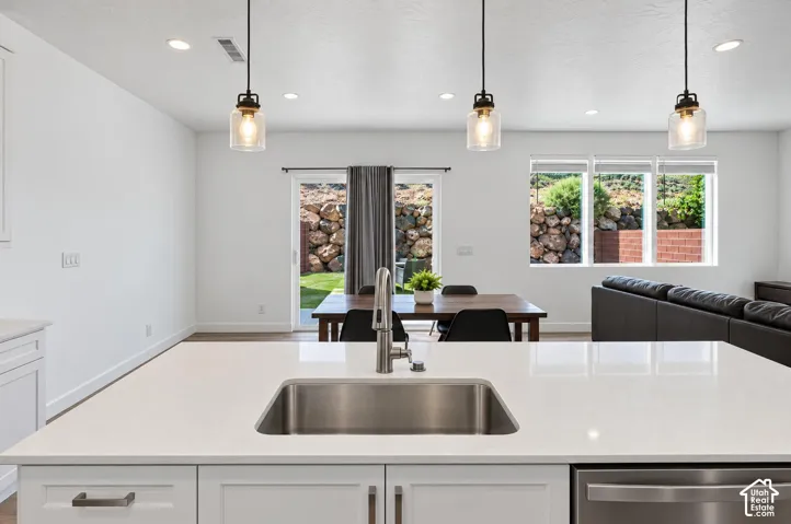 White kitchen island with an undermount stainless steel sink, brushed nickel faucet, and white shaker-style cabinetry