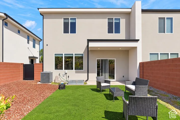 Rear exterior featuring a patio with recessed lighting, sliding glass door, artificial turf, and a red brick privacy wall