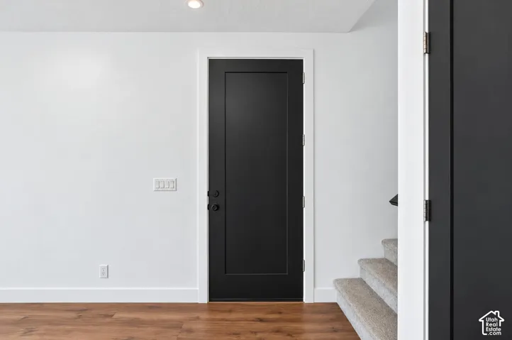 Black panel door with matte black hardware, white trim, and light wood-finish flooring