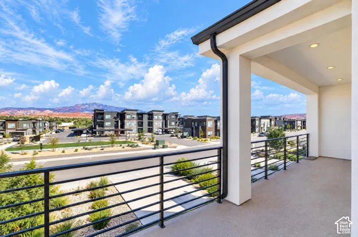 Covered balcony with recessed lighting, black horizontal railings, and a concrete-finish floor