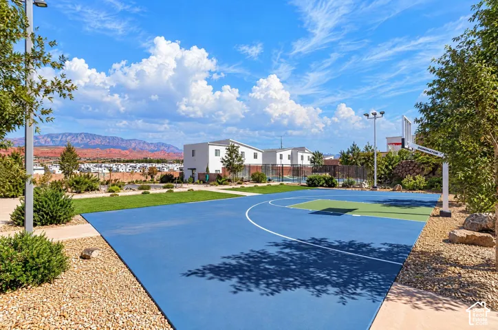 Basketball court with a blue and green playing surface, surrounding gravel landscaping, and distant mountain scenery