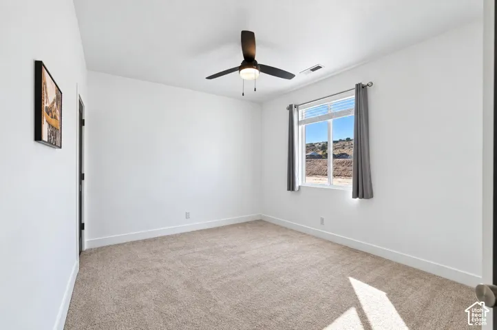 Plush carpet flooring, a ceiling fan with light fixture, a window with horizontal blinds, and a solid interior door with dark hardware