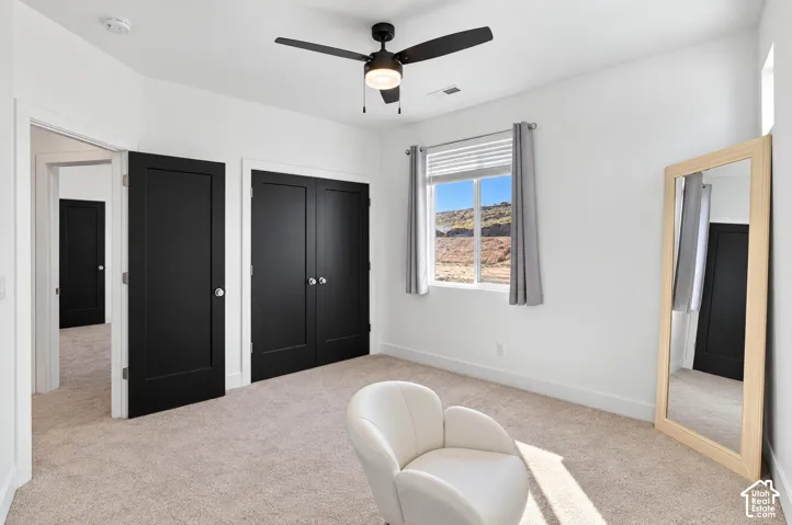 White walls with an accent of black doors, carpet flooring, and a ceiling fan