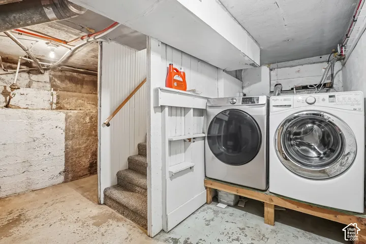 Dedicated laundry area featuring a front-loading washer and dryer, with permanent shelving and a carpeted staircase