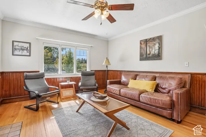 Hardwood flooring, wood paneling, crown molding, ceiling fan, and multiple windows