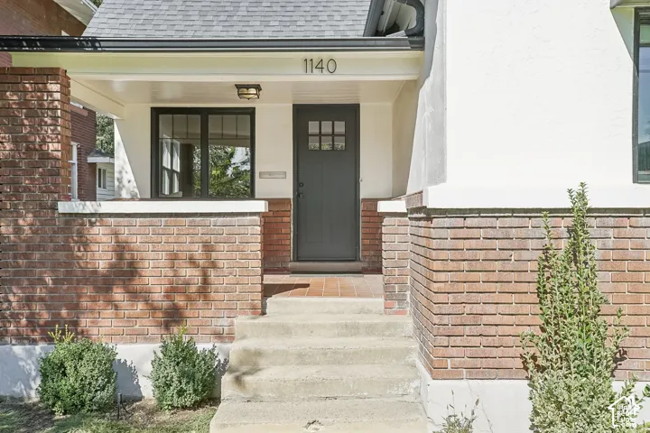 Brick and stucco exterior with dark trim windows, covered entry, and a dark paneled front door