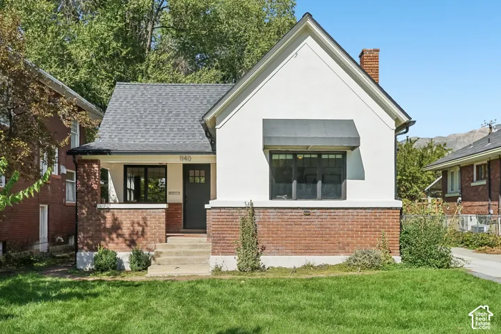Stucco and brick exterior with a pitched roof, front entry porch, and a window awning