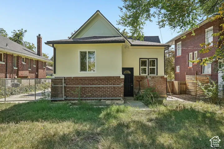 Rear facade featuring a prominent gable, light-colored stucco, and red brick detailing