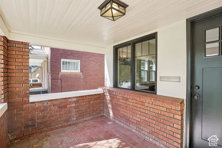 Brick-clad exterior porch featuring a paneled ceiling, recessed lighting, and a dark-framed window