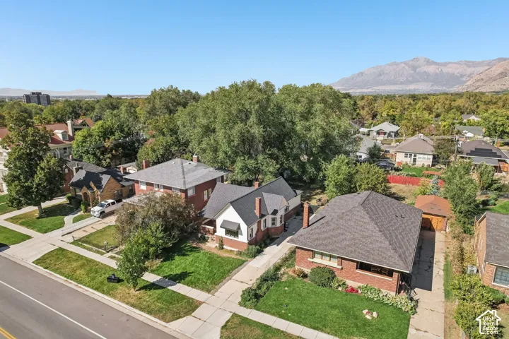 Brick exterior home with a gabled roof, mature trees, and an attached garage