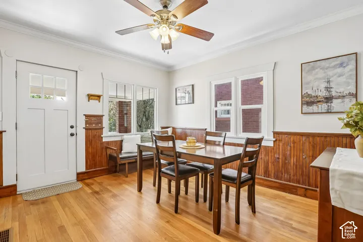 Hardwood flooring, wood paneling, white crown molding, multi-pane windows, and a glass-paneled door