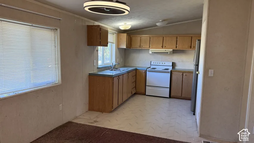 Kitchen featuring wood-finish cabinetry, white appliances, and a double basin sink