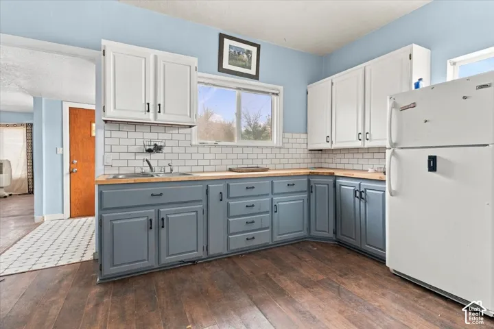 Kitchen featuring wood-finish flooring, white subway tile backsplash, and light wood countertops