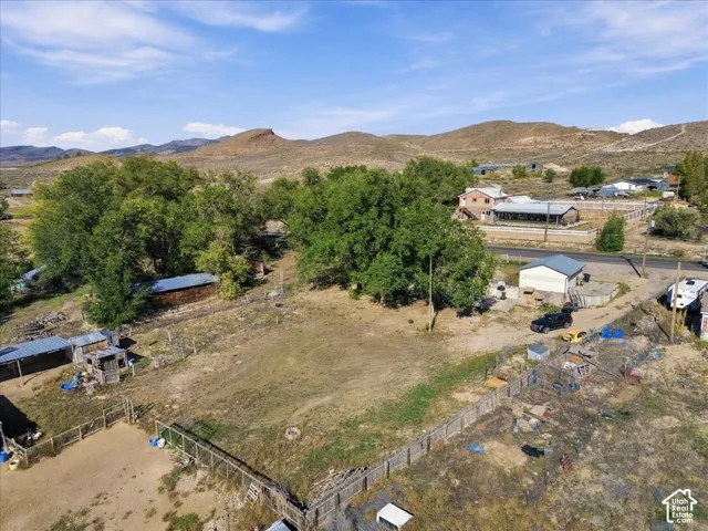 Expansive land parcel with surrounding fencing, mature trees, and mountainous backdrop