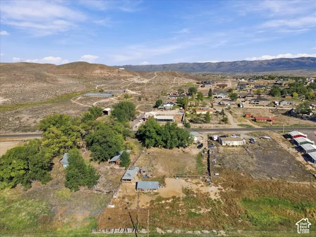 Expansive land parcel featuring multiple structures, mature trees, and mountainous surroundings