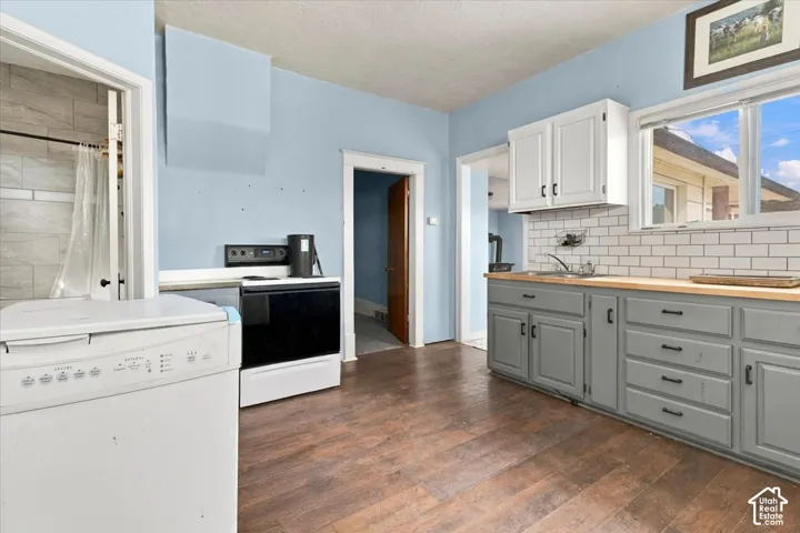 Wood-finish flooring, white subway tile backsplash, light wood countertops, white upper cabinetry, and gray lower cabinetry