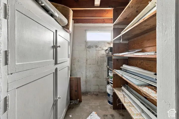 Built-in cabinetry, wood shelving, and exposed ceiling joists