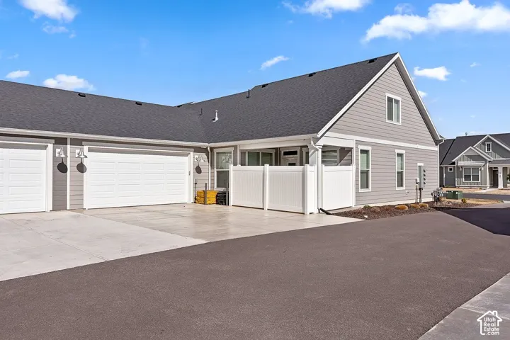 Attached garages with panel doors, private patio with privacy fencing, and asphalt driveway