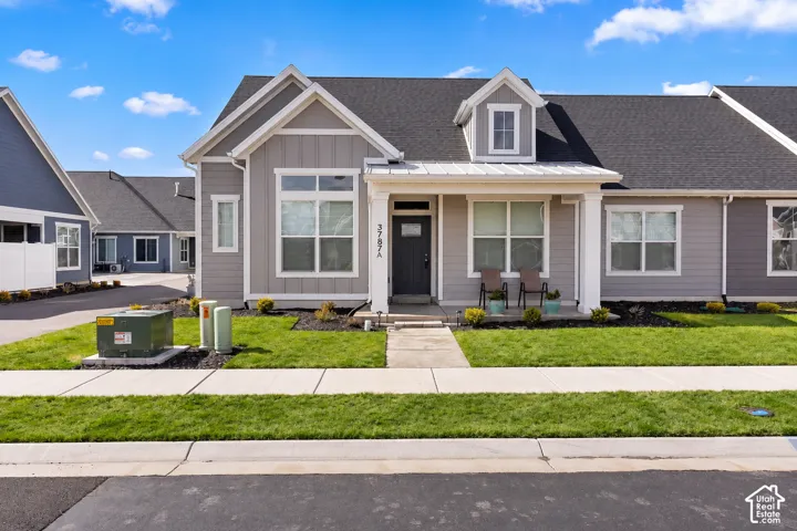 Modern exterior featuring gray siding, white trim, a dormer window, covered entry, and a dark asphalt shingle roof