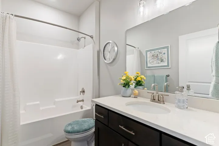 White tub and shower combination with brushed nickel fixtures, dark wood-finish vanity with a light countertop, and a large wall-mounted mirror