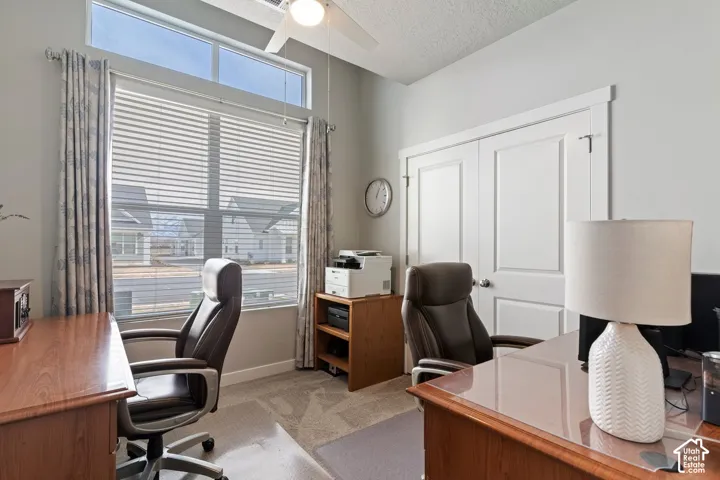 Carpeted room featuring a ceiling fan, a large window with blinds and drapes, and white double closet doors