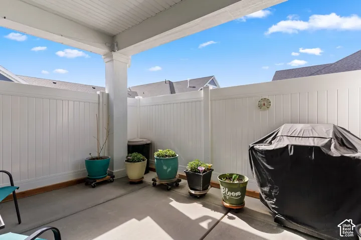Covered patio with a concrete surface and white privacy fencing