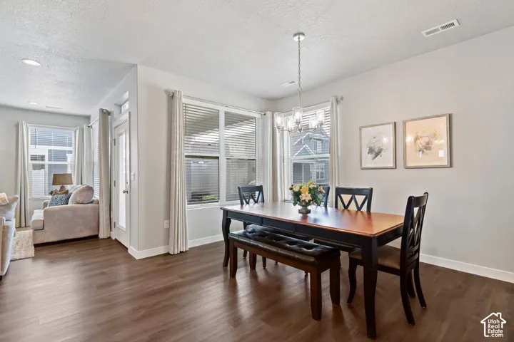 Wood-finish flooring throughout, a modern chandelier, bay windows with blinds, a glass-paneled door, and recessed lighting