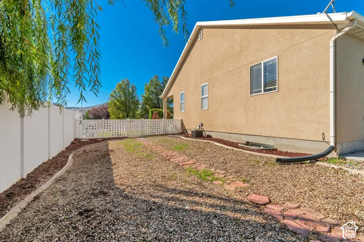 Stucco exterior with multiple windows, a white privacy fence, a lattice fence, and a gravel-covered ground