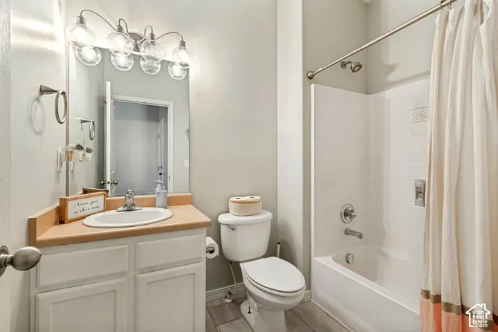 Vanity with integrated sink, overhead five-bulb light fixture, built-in bathtub and shower combination, and wood-finish flooring