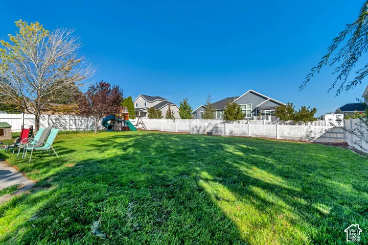 Expansive lawn area enclosed by a white privacy fence