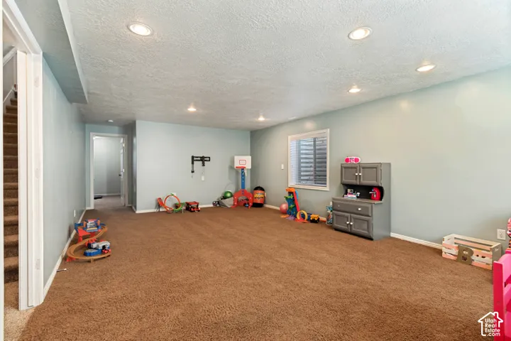 Recessed lighting, light-colored walls, carpeted flooring, and an egress window