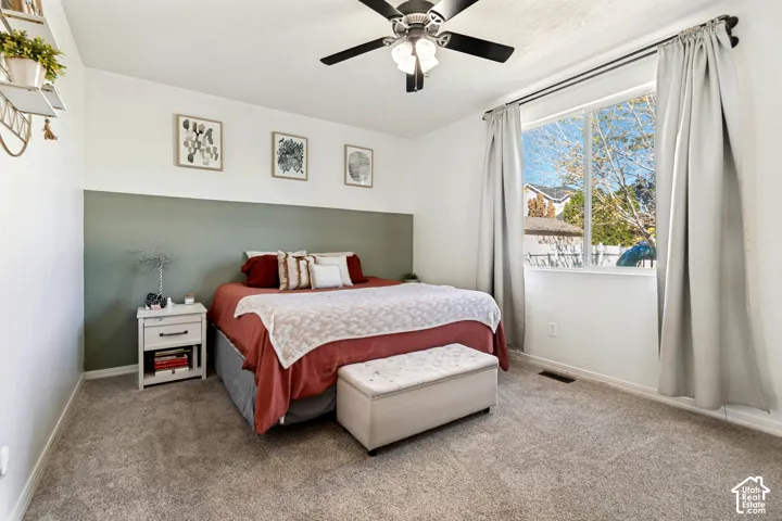 Wall-to-wall carpeting, ceiling fan, and large window with exterior view