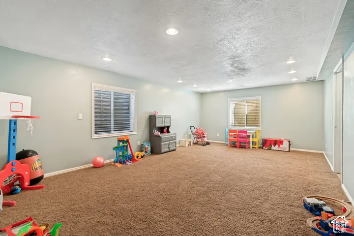 Expansive carpeted room featuring recessed lighting and two windows with blinds
