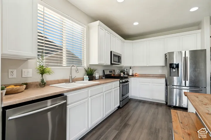 Kitchen featuring white cabinetry, light countertops, wood-finish flooring, recessed lighting, and stainless steel appliances
