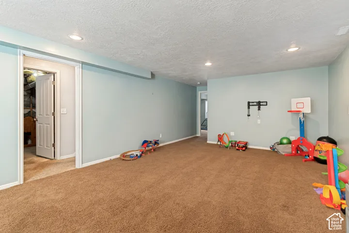 Recessed lighting, light blue wall paint, brown carpeting, white trim, and white doors