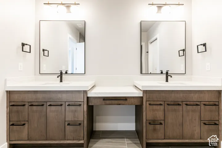 Dual vanities with integrated sinks and white countertops, individual mirrors with black frames, and wood-finish cabinetry
