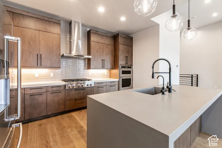 Gourmet kitchen with wood-finish cabinetry, stainless steel appliances, and a large island featuring a built-in sink and matte black faucet