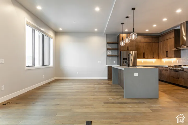 Wood-finish flooring, recessed lighting, and a kitchen island with pendant lights