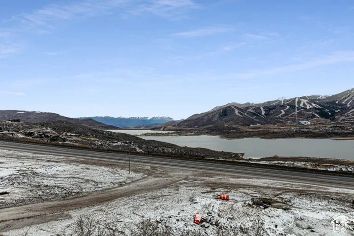 Mountain scenery with a body of water, alongside a paved road